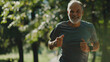 senior smiling  man in fitness wear running in a park