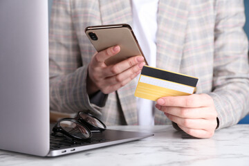 Canvas Print - Online payment. Woman with laptop, smartphone and credit card at white marble table, closeup