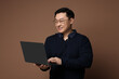 © New Africa - Portrait of happy man with laptop on brown background