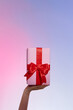 © Marc Tran/Stocksy - Female hands hold a pink gift box with a red bow and slide it up