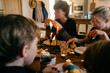© Lea Jones/Stocksy - teen boy eating orange during family breakfast/brunch