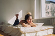 © Amor Burakova/Stocksy - Young woman resting lying on bed
