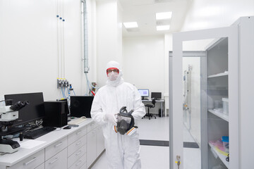 Researcher Walking At Clean Room Holding Helmet