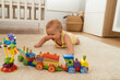 © Manu Padilla/Stocksy - Cute baby playing with toys on carpet in apartment