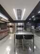 A kitchen with stainless steel appliances and a large counter. The counter is surrounded by black chairs and a silver table. The kitchen is well-lit and has a modern, sleek design