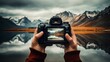 The hands of a dedicated photographer holding a digital camera, capturing the reflection of mountains on a calm lake, displayed vividly on the camera screen.