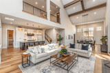 Fototapeta  - Beautiful living room interior in new luxury home with view of kitchen. Home interior with hardwood floors and open floorplan showing dining room, kitchen, and living room. Has high vaulted ceilings