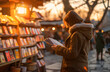 A woman engrossed in a book at an outdoor market during a picturesque sunset.