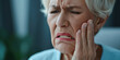 Mature woman suffers acute toothache, periodontal disease, cavities or jaw pain almost crying with pain ache. Senior old retired female pressing sore cheek on studio background