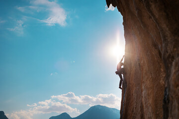 Wall Mural - Rock climber on the background of high mountains and blue sky