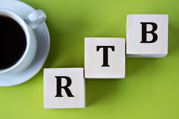 RTB - acronym on wooden big cubes on green background with cup of coffee