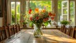 A well-lit dining room with a polished wooden table and chairs, accented by a glass vase filled with a profusion of colorful flowers, creating a cheerful atmosphere