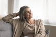 © fizkes - Attractive dreamy middle-aged woman spend weekend time at home, sitting on sofa, looking away and smiling, feels satisfied, relish carefree life, enjoy peace and solitude, dreaming about bright future