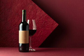 Poster - Bottle and glass of red wine on a red background.