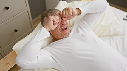 Wall Mural - Cheerful middle age grey-haired man having fun, wearing pyjama, covering eyes with hands in a playful blind game. smiling joyfully in bedroom, delivering a funny and heartwarming surprise.