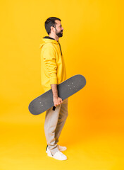 Wall Mural - Full-length shot of man over isolated yellow background with a skate