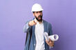 Young architect man with helmet and holding blueprints over isolated purple background frustrated and pointing to the front