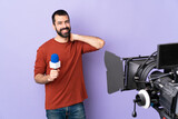 Fototapeta  - Reporter man holding a microphone and reporting news over isolated purple background laughing