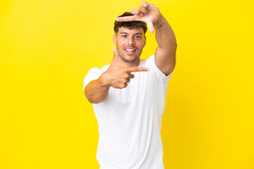 Sticker - Young caucasian handsome man isolated on yellow background focusing face. Framing symbol