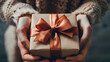 Women's hands hold an elegant gift box. The gift is wrapped in wrapping paper and decorated with a bow. The photo was taken in high resolution. It is a very detailed