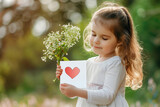 Fototapeta Boho - Adorable little girl offering flowers and heart shaped card to her mom on a mothers day