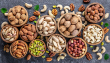 Mixed Nuts In Wooden Bowls On Black Stone Table. Almonds, Pistachio, Walnuts, Cashew, Hazelnut. Top View Nut Photo.