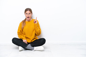 Wall Mural - Young caucasian woman sitting on the floor isolated on white background thinking an idea pointing the finger up