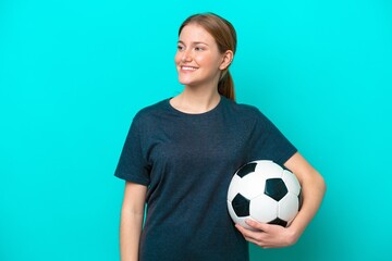 Wall Mural - Young football player woman isolated on blue background looking to the side and smiling