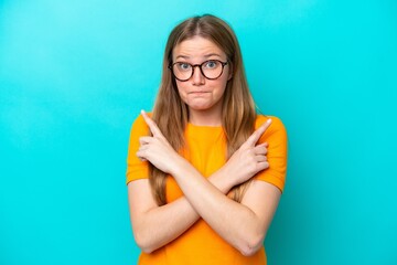 Wall Mural - Young caucasian woman isolated on blue background pointing to the laterals having doubts