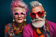 Extravagant senior couple portrait. Fashionable grandfather and grandmother wearing elegant clothes. Stylish cute old man and woman on colored background
