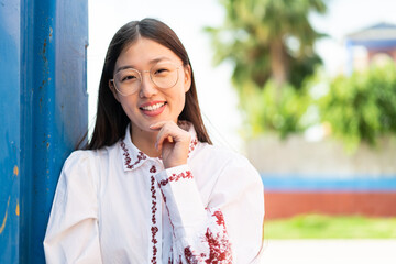 Wall Mural - Young Chinese woman at outdoors With happy expression