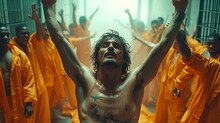 A Man With His Arms In The Air In Front Of A Group Of Men In Orange Robes In A Jail Cell.