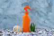 SPF. A bottle of sunscreen on the pebbly seashore is decorated with seashells. Sun lotion. UVA UVB. Body care. Blue background.