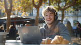 Fototapeta Perspektywa 3d - A young man in casual and headphones works on his laptop at an outdoor cafe