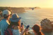 Group of people photographing a plane flying over the ocean, capturing the scenic moment