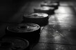 Monochrome gym setting with Weight plates scattered across a dark gym floor with contras