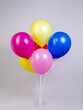 Colorful bright balloons on a stand on a gray background