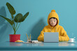 © Prime Lens - 3d render of a young guy wearing a yellow hoodie, sitting at a blue table, using a laptop with one hand on the keyboard to surf the internet, accompanied by a green plant in a red pot