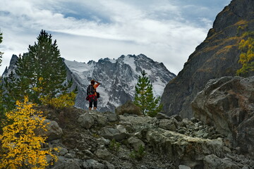 Poster - Russia. Kabardino-Balkaria. A tourist with a backpack and a camera admires the beauty of the snow-capped peaks of the Caucasus Mountains at sunset on an autumn day.