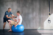 © peopleimages.com - Amputee, exercise ball and rehabilitation with physiotherapist at gym for training with motivation. Fitness, professional and patient with disability for wellbeing with workout, health and happy