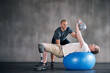 © peopleimages.com - Trainer, man with a disability and prosthetic leg and dumbbell in physiotherapy, studio and gym ball. Male people, physiotherapy and amputee for wellness, fitness and exercise in rehab center