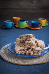 Serving of fruit biscuit cake on a table with colourful cups and saucers