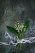Lilies of the valley flowers with ribbons on abstract dark background. Romantic gentle symbol of spring season. flat lay