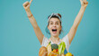 A jubilant woman holds a paper bag full of fresh produce.