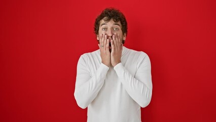 Poster - Shocked young hispanic man in sweater, fear and amazement etched on his face. alone against a red background, expressing disbelief and excitement.