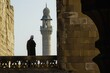 A man is standing on a balcony, gazing at a tall tower in the distance, A muezzin calling to prayer from a minaret, AI Generated