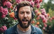 Man with beard wears headphones, sings in front of flowers