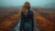 the back of a woman's head as she walks down a path in a field on a foggy day.