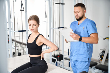 Wall Mural - Doctor questioning female patient in kinesiology clinic