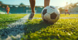 Close-up of soccer ball on  green field with blurred players in background. Sunlight shining on the grass, creating vibrant and dynamic atmosphere. Concept of sports, teamwork, and outdoor activities.